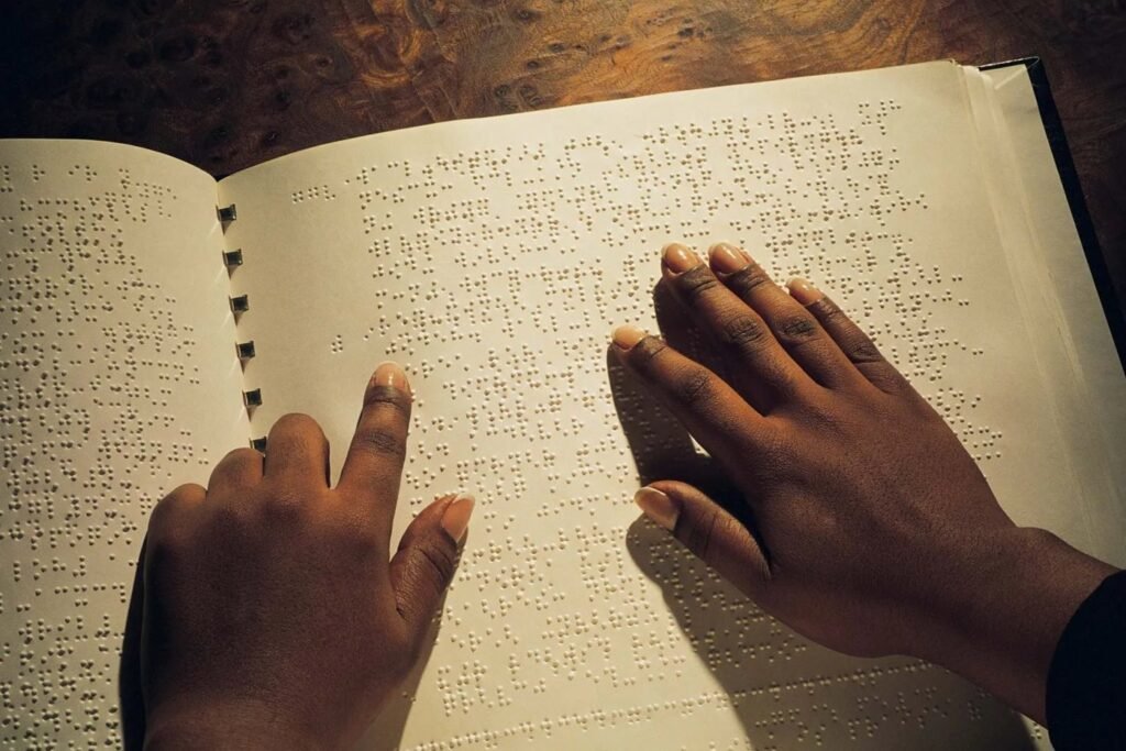 Hands reading a page of a Braille book