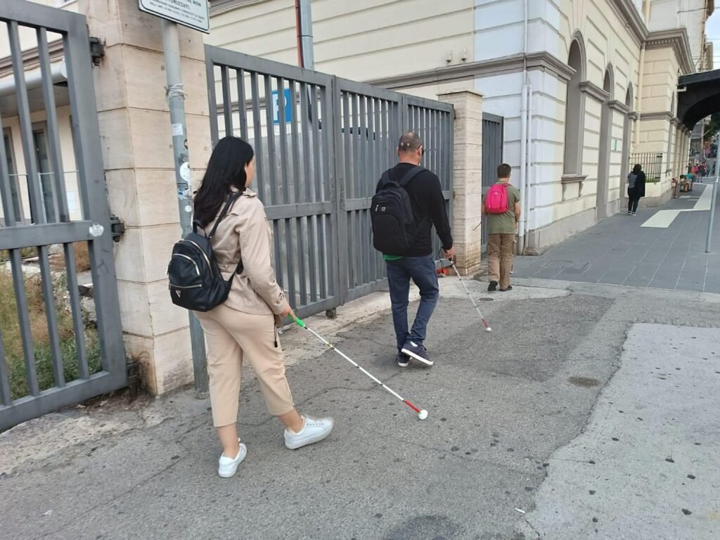 Person walking along a street using a white cane