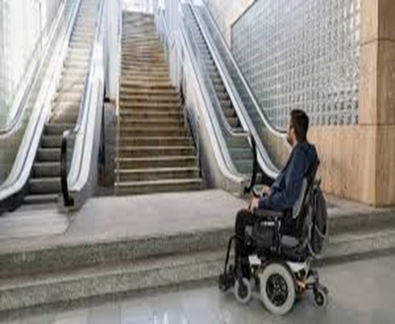 Stairs beside an escalator with a person in a wheelchair below