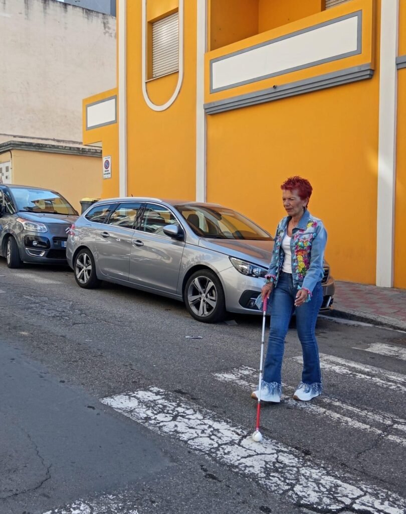 Person with a white cane crossing a street at a pedestrian crossing