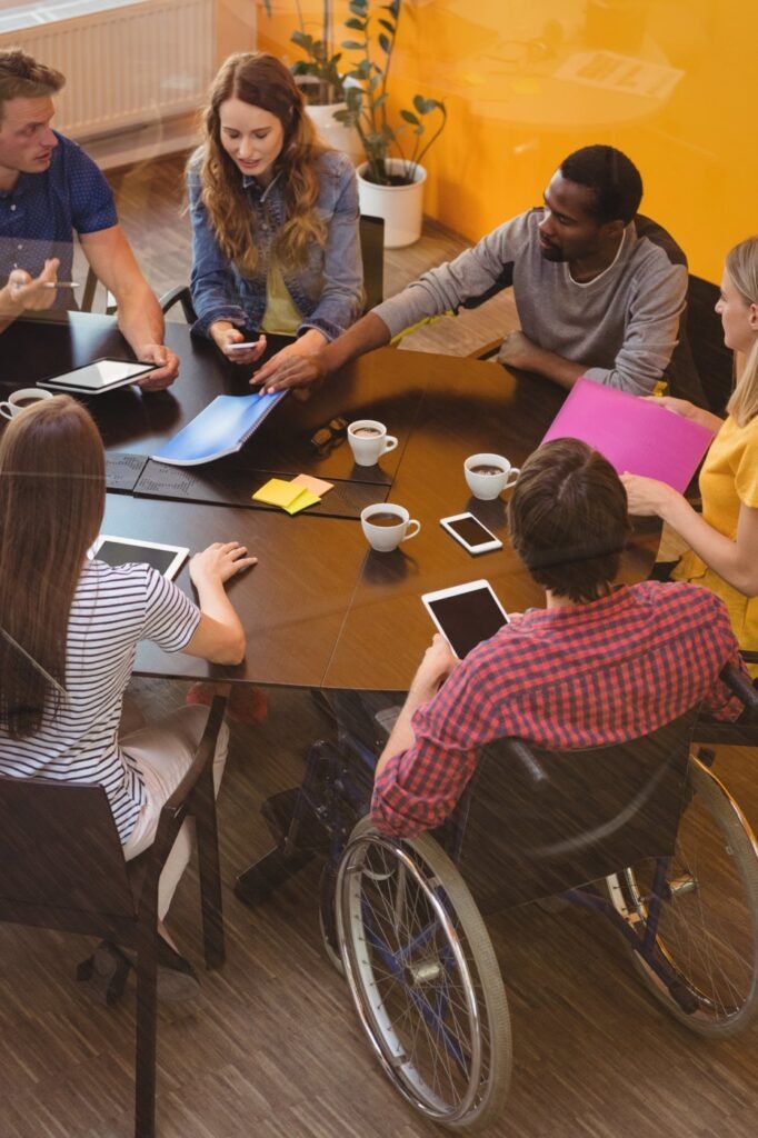 Diverse group of young people, including a wheelchair user, working together around a table